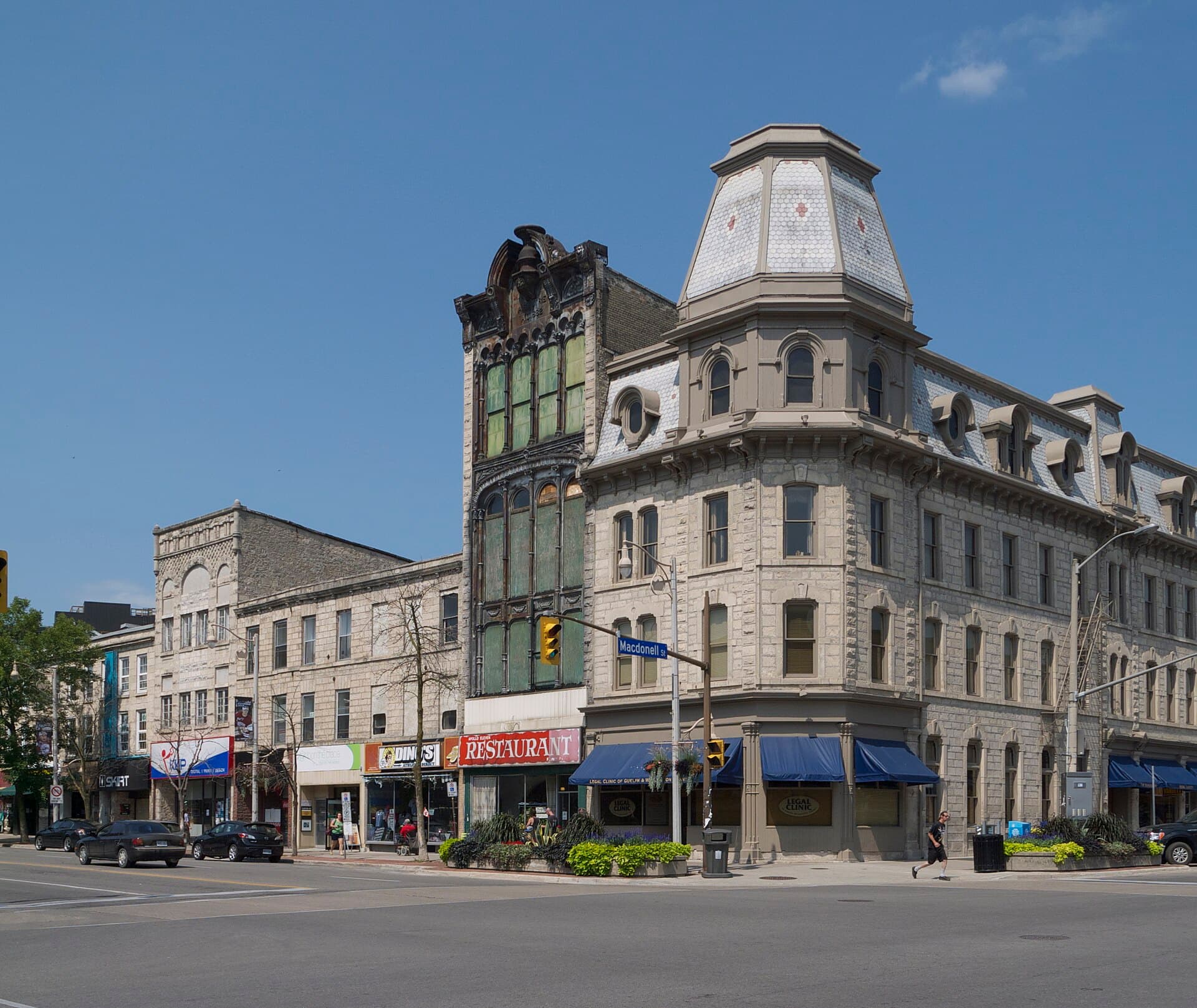 Ornate 19th-century stone commercial buildings with a mansard-roofed corner tower on Wyndham Street, Guelph