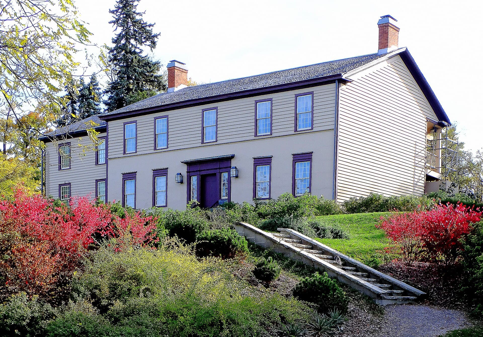 Battlefield House, a two-storey clapboard house on a hillside in autumn, Stoney Creek