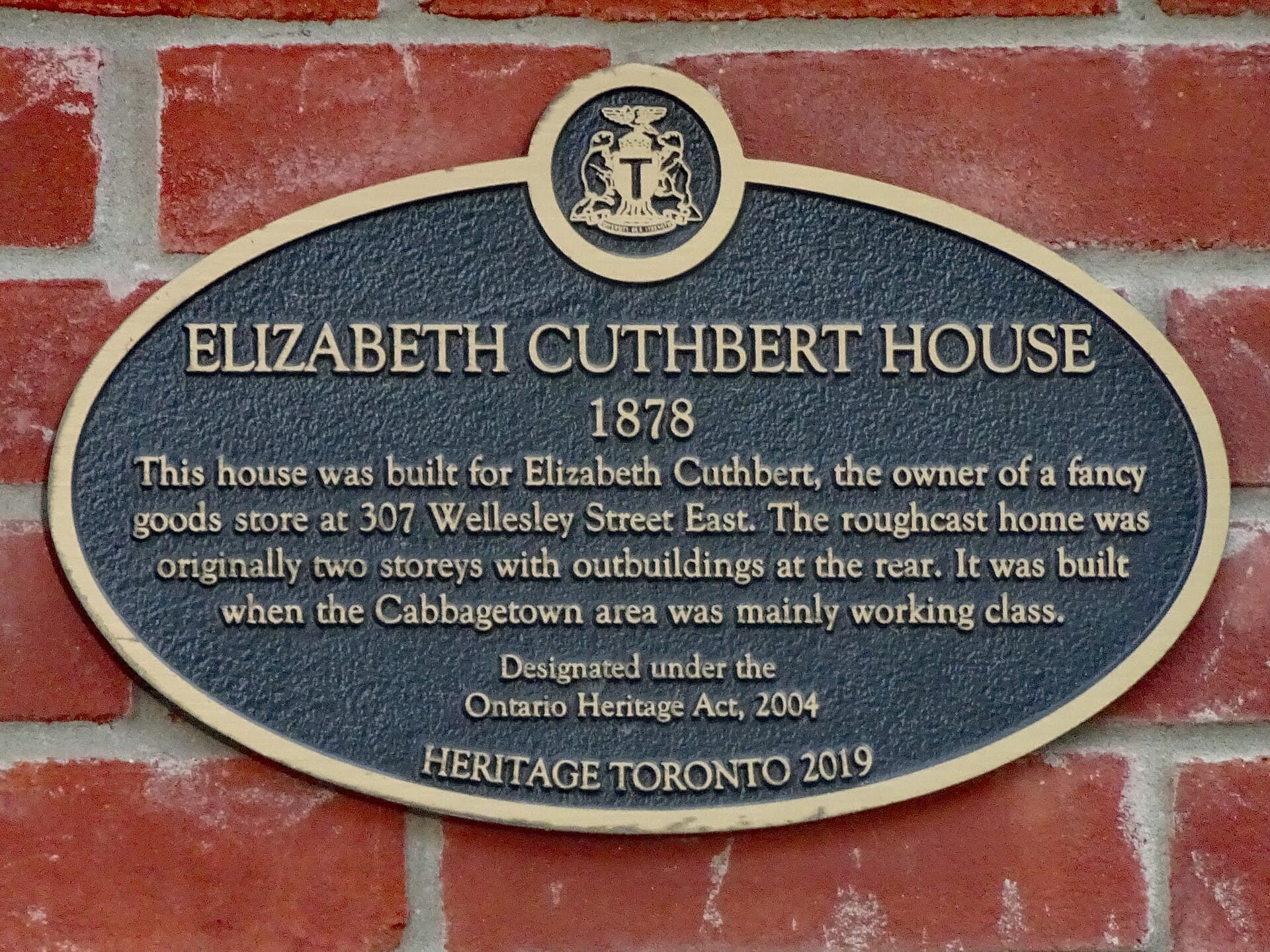 Oval heritage plaque on red brick reading 'Elizabeth Cuthbert House, 1878 … Designated under the Ontario Heritage Act, 2004'